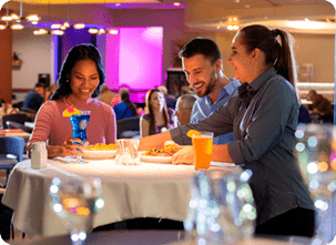 couple eating dinner in large dining room as waitress serves them